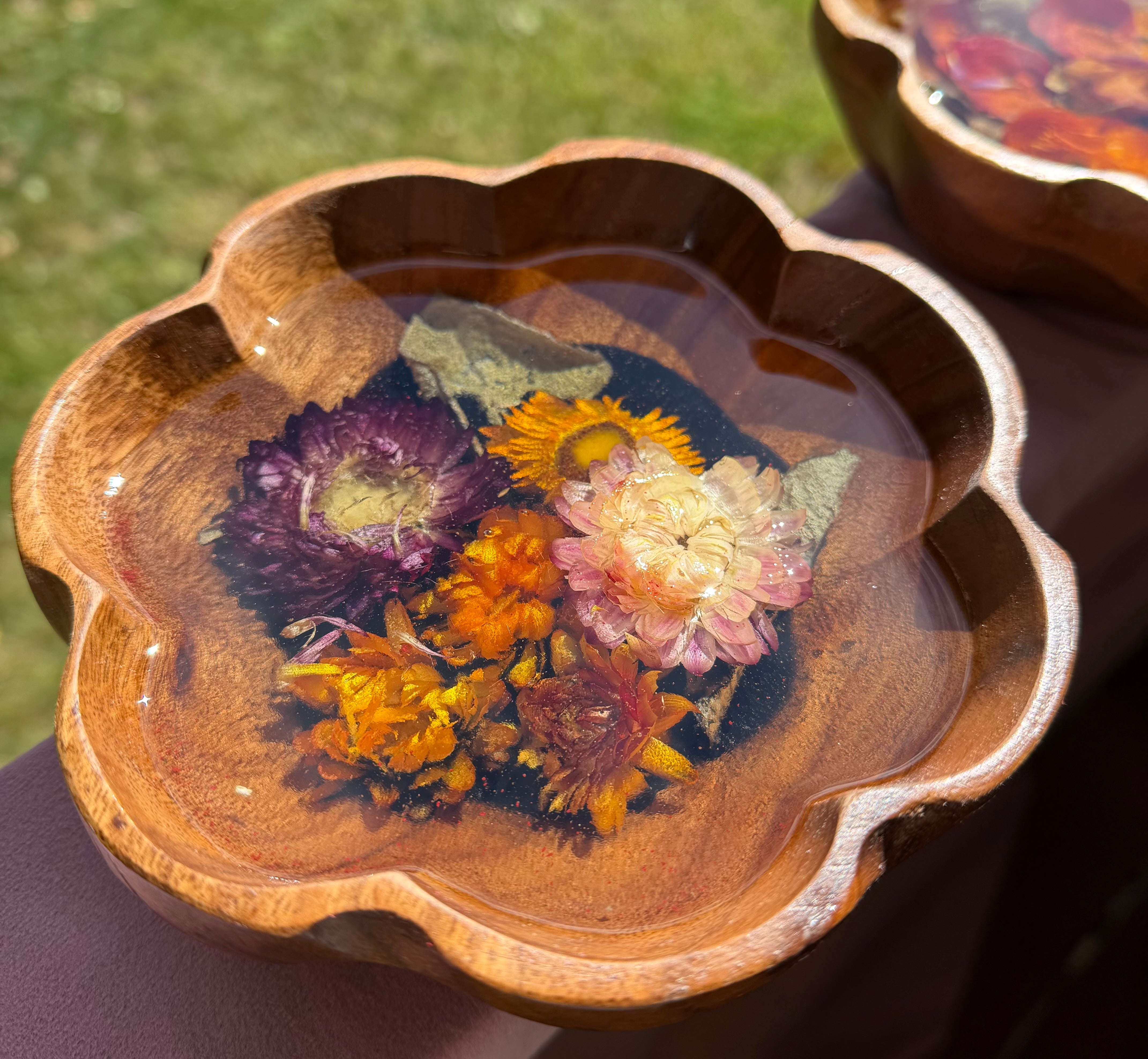 Small scalloped wooden bowl with purple, pink, orange, and gold strawflowers set in resin over a black center