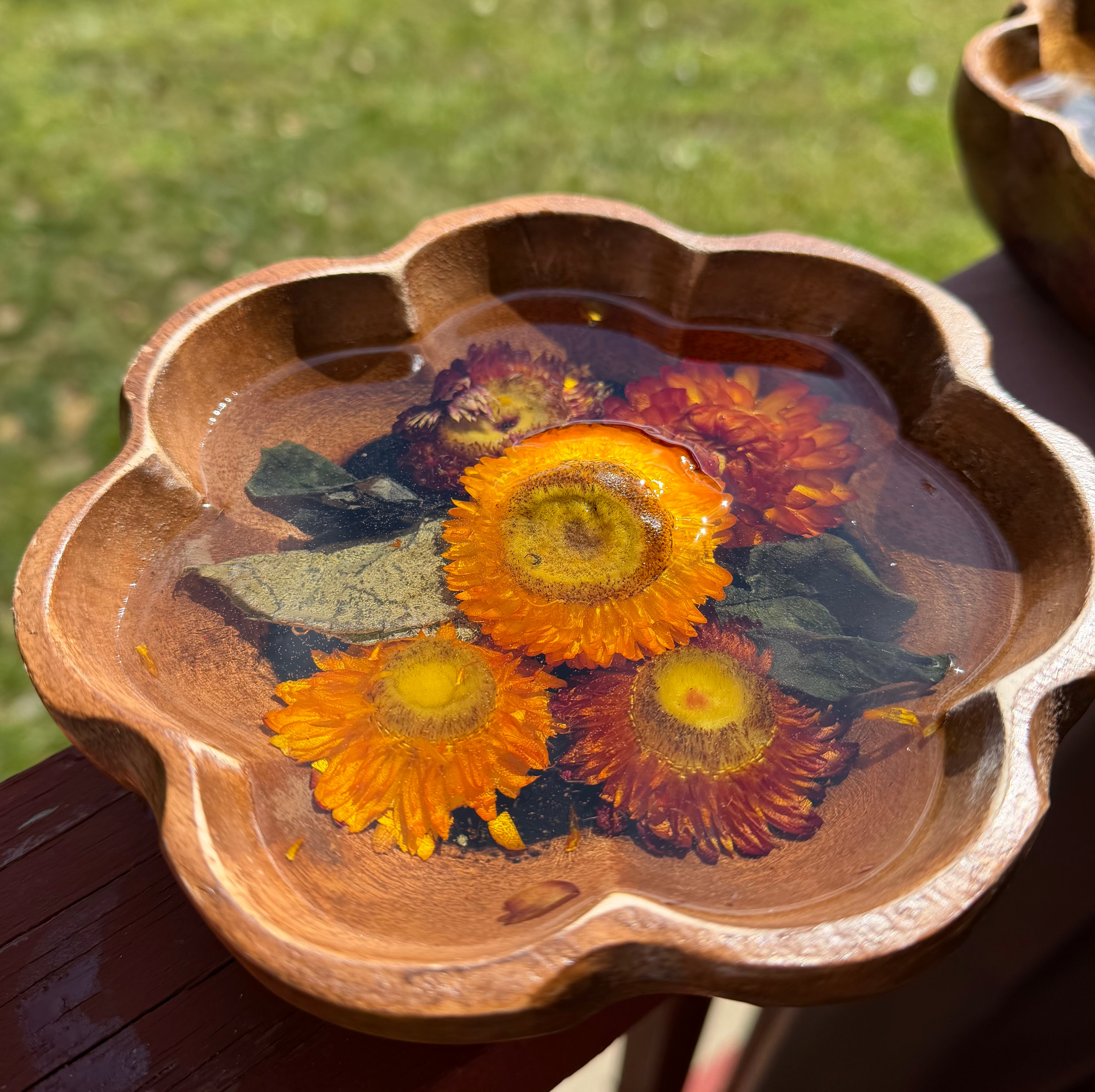 Scalloped wooden bowl with preserved orange strawflowers and green leaves in resin