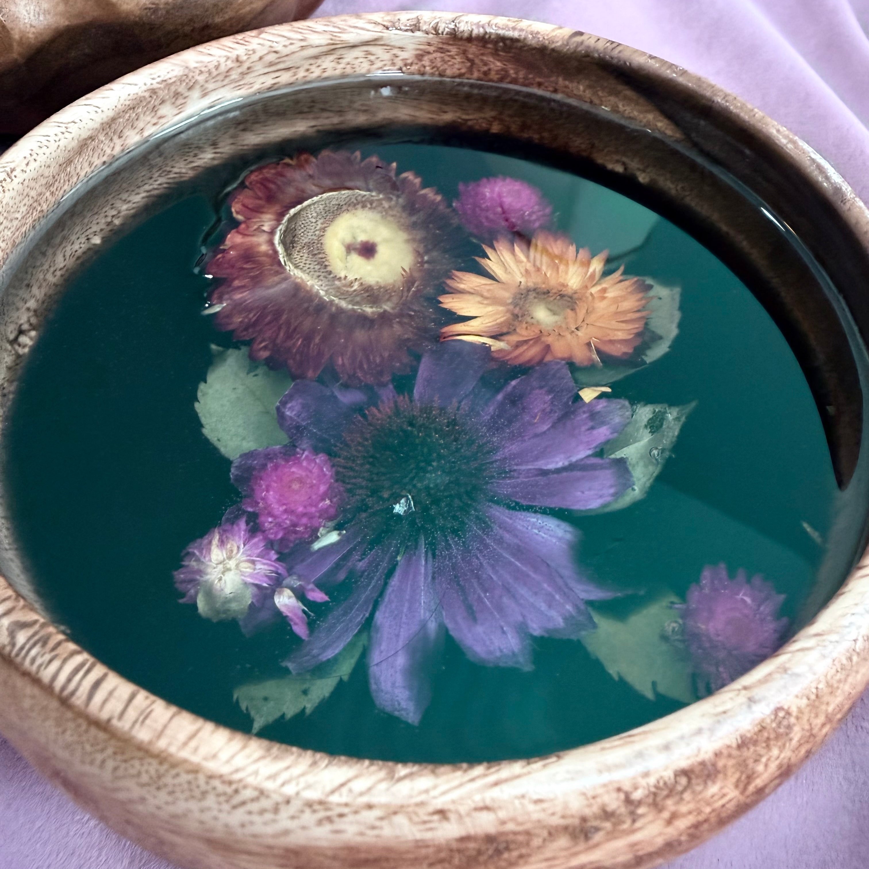 Round wooden bowl with a purple coneflower, magenta and orange strawflowers, and purple pom-pom blooms set in black resin