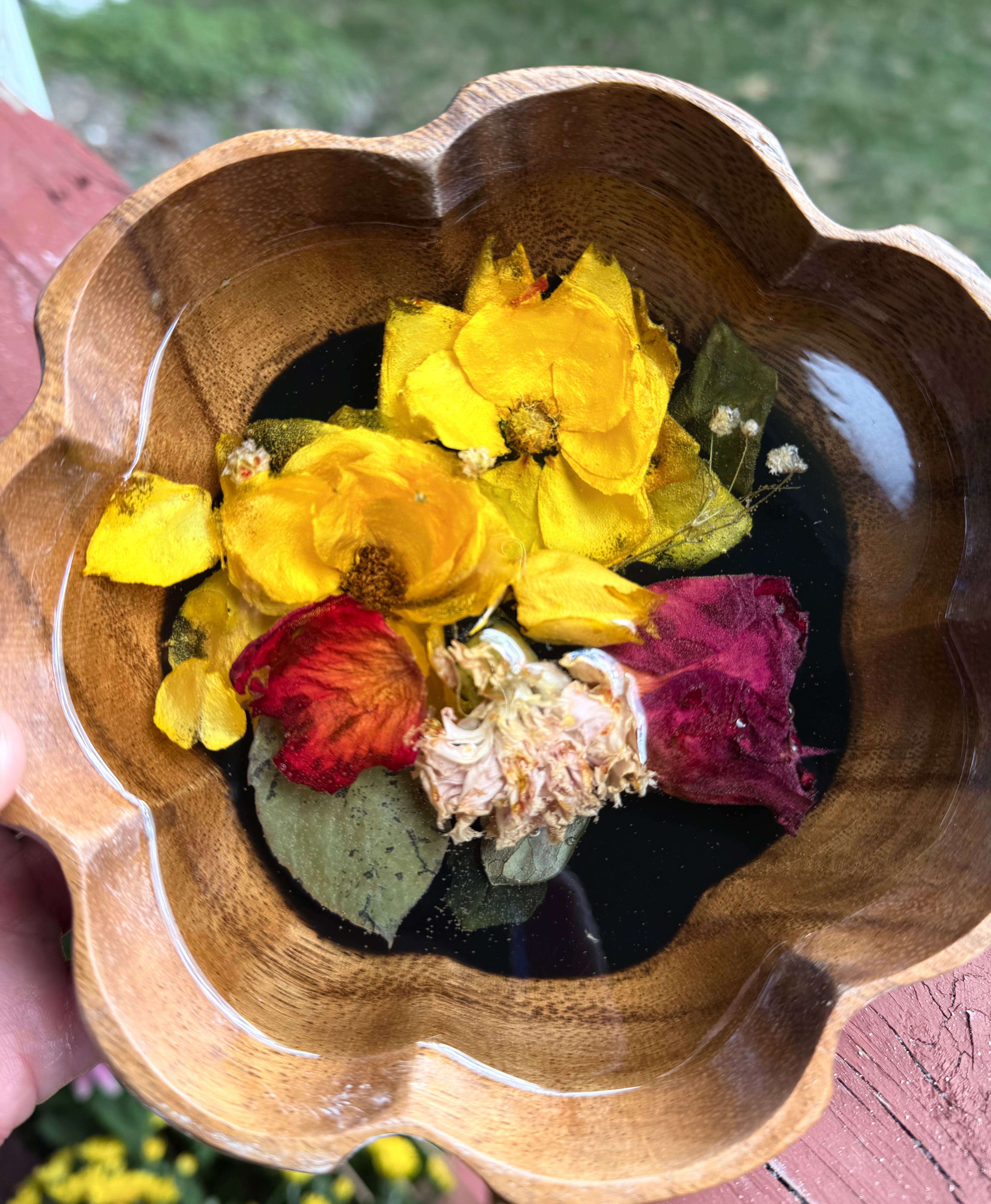 Small scalloped wooden bowl with yellow roses, a red rose, crimson petals, and a cream bloom set in black resin