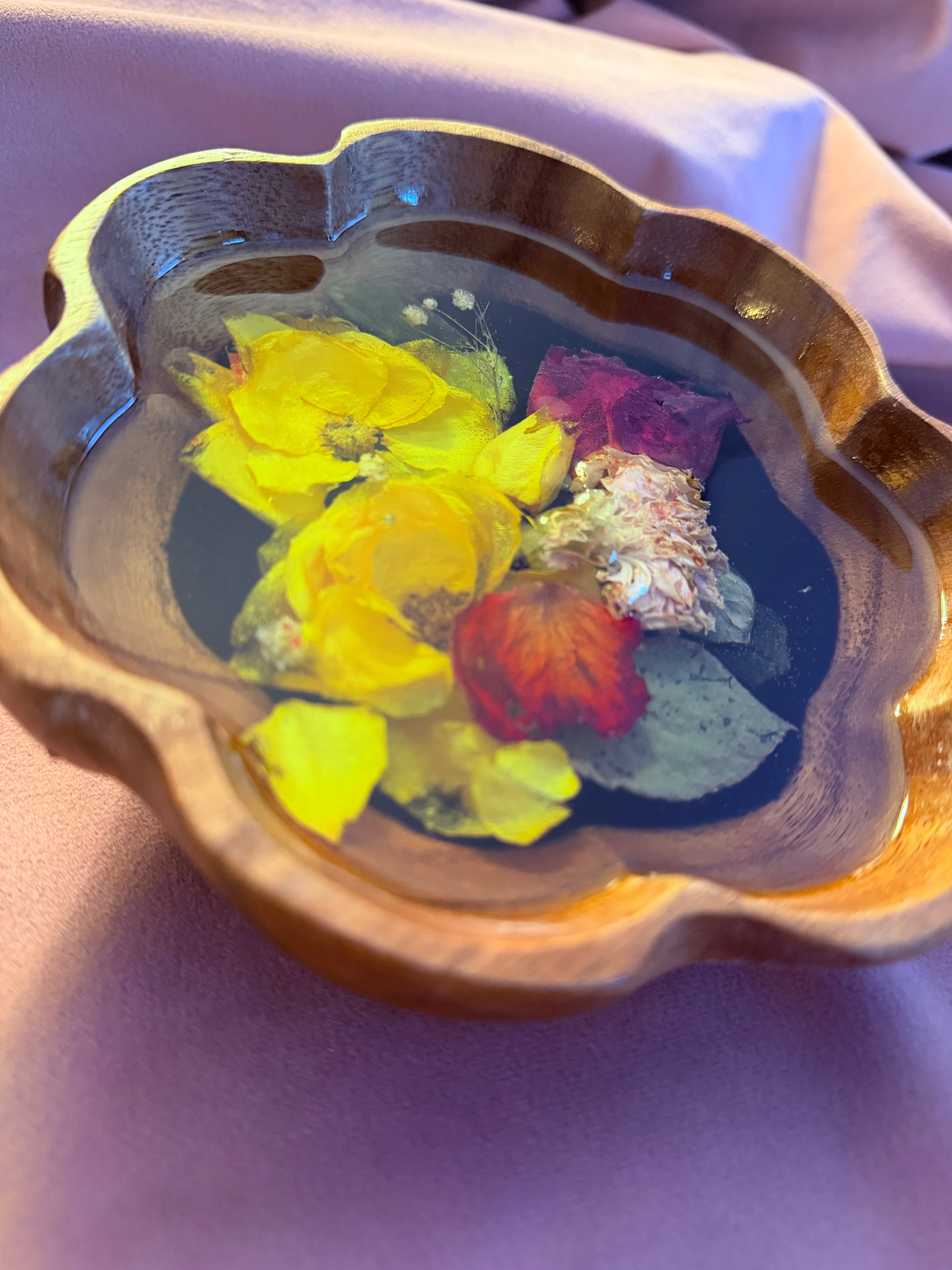 Scalloped wooden bowl with preserved yellow and red roses and green leaves over black resin, on lavender fabric