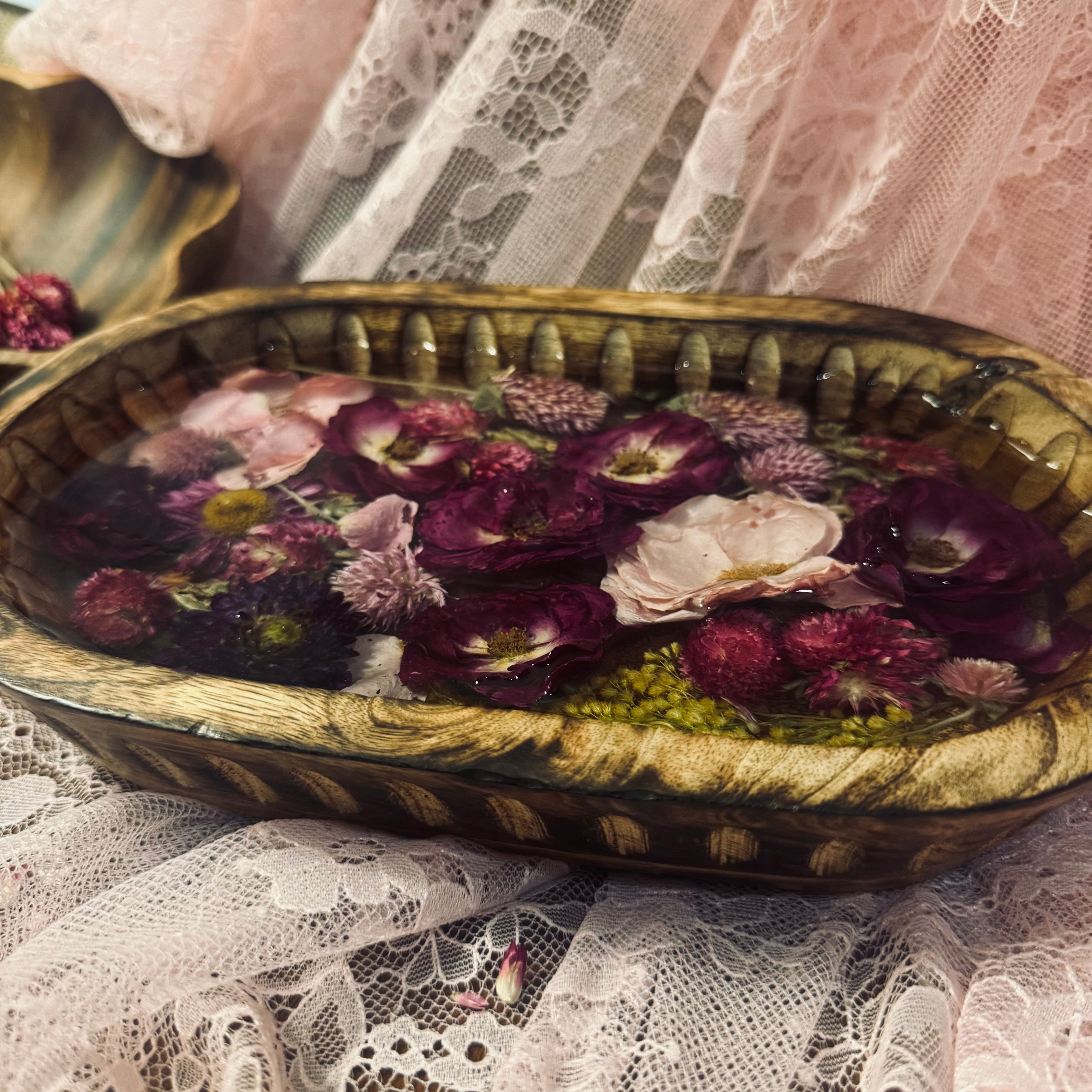 Mango wood oval keepsake bowl with purple and pink preserved roses and golden goldenrod sprays set in clear resin, styled on pink and white lace