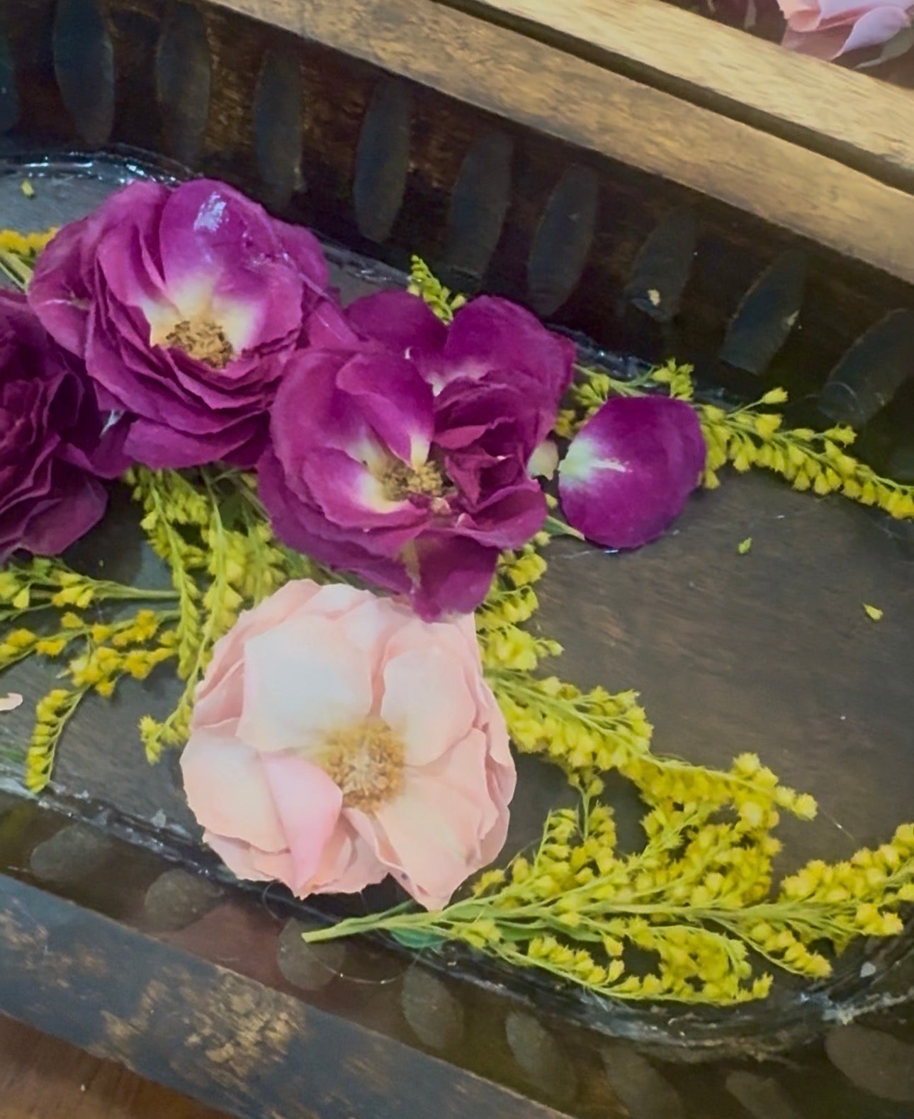 Wood bowl filled with deep purple roses and a blush pink rose accented with yellow solidago, sealed in glass-like resin