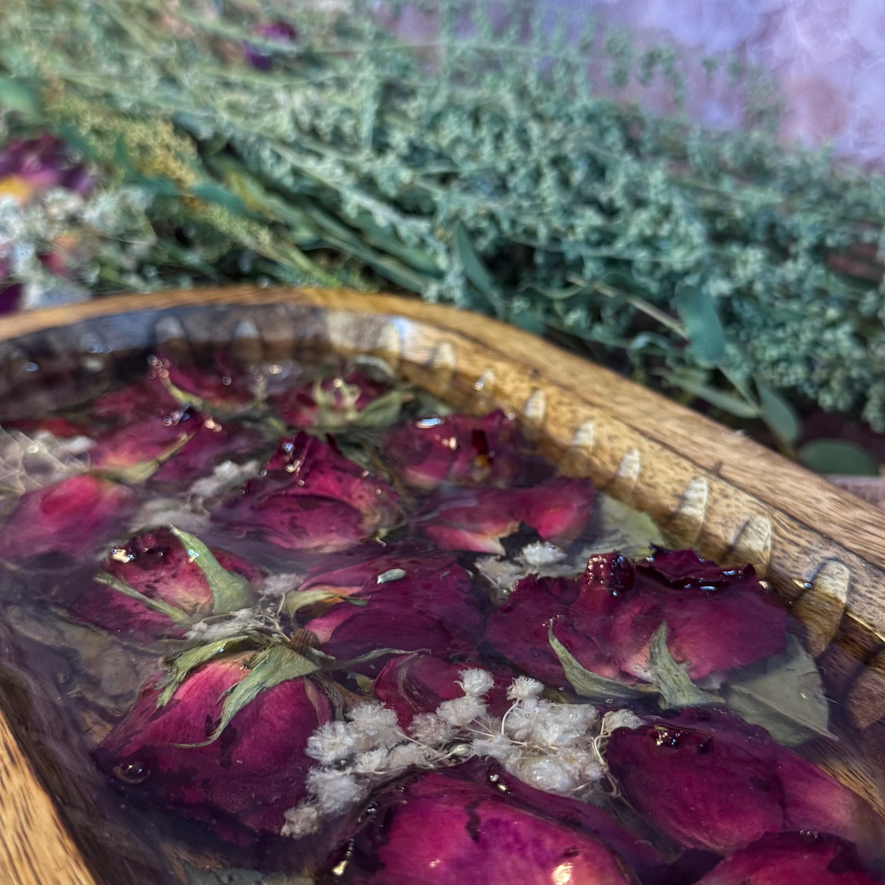 Carved wooden dish of preserved red roses, baby's breath, and greenery set in clear resin