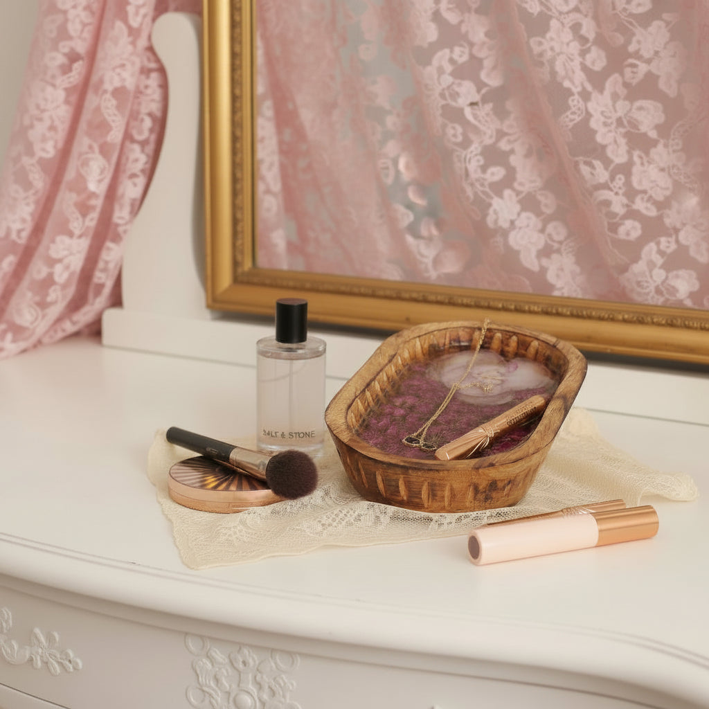 An oval mango wood bowl filled with a pale pink rose and deep pink rosebuds preserved in clear resin, photographed on a plain background.